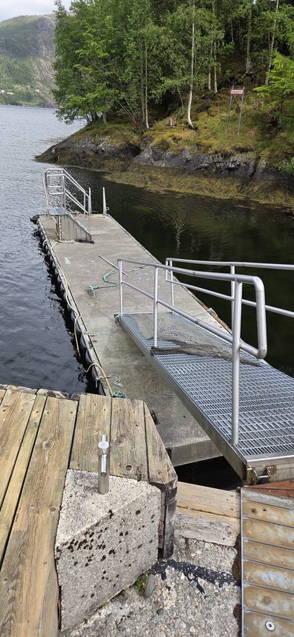 Ferdig flytebrygge med ny landgang i galvanisert rist, i en fjordarm.